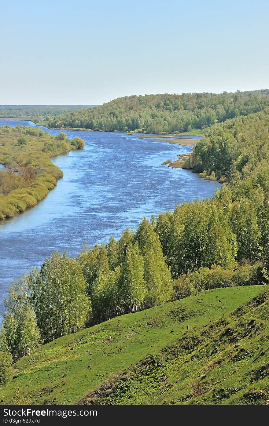 River in the middle of green hills.