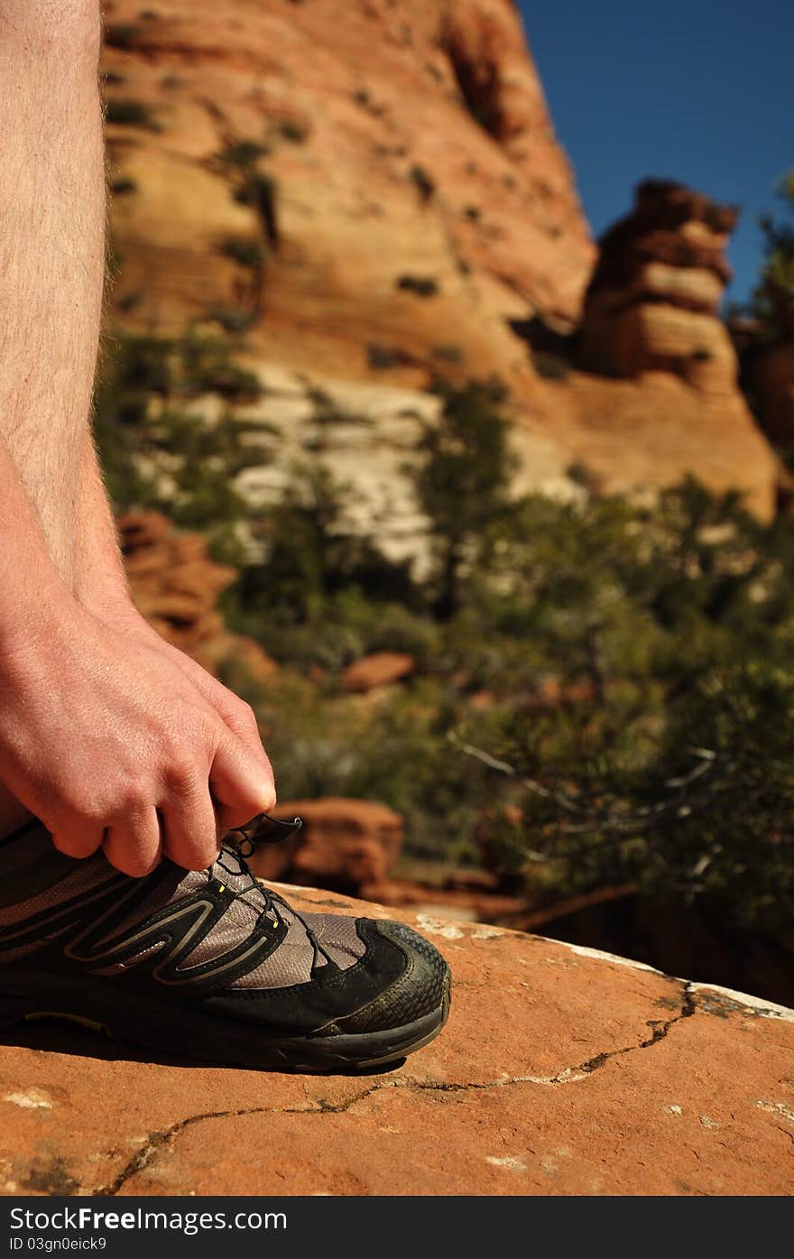 A man tying his hiking shoe in Zion National Park Utah. A man tying his hiking shoe in Zion National Park Utah