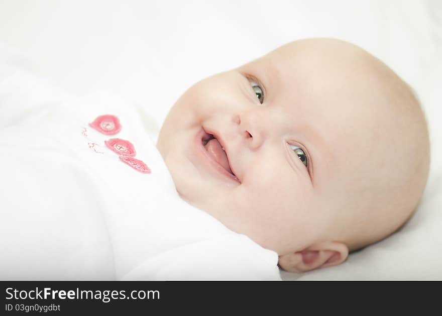 A small child lies on a white background and smiling. A small child lies on a white background and smiling