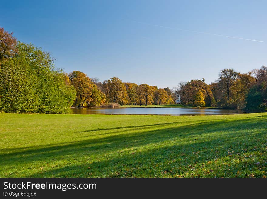 Beautiful green meadow and the pond in the autumn park. Beautiful green meadow and the pond in the autumn park