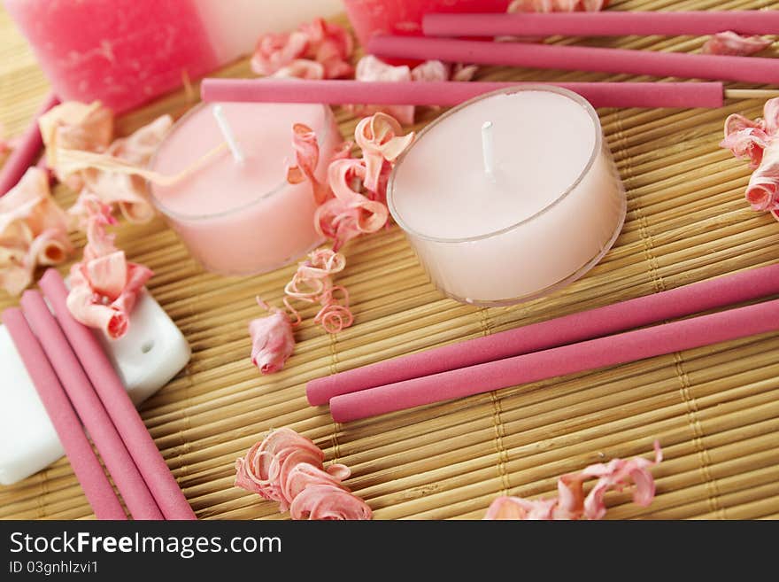 Spa treatment in bright pink and white palette, petals, candles, and arotatizirovannye sticks on a wooden bamboo rug