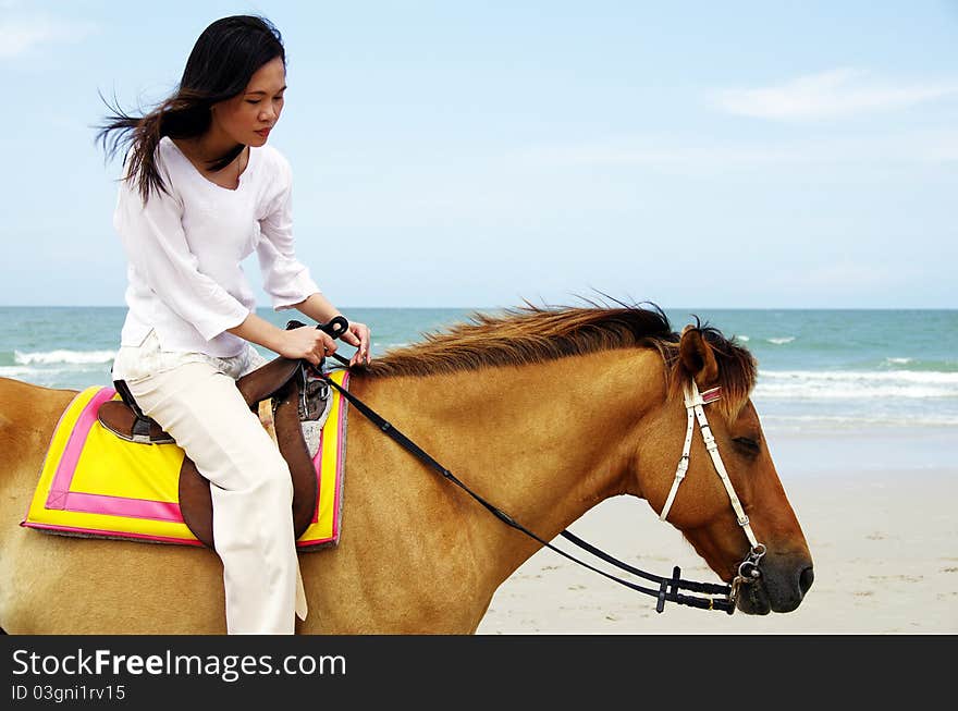 Young woman riding a horse on the beach