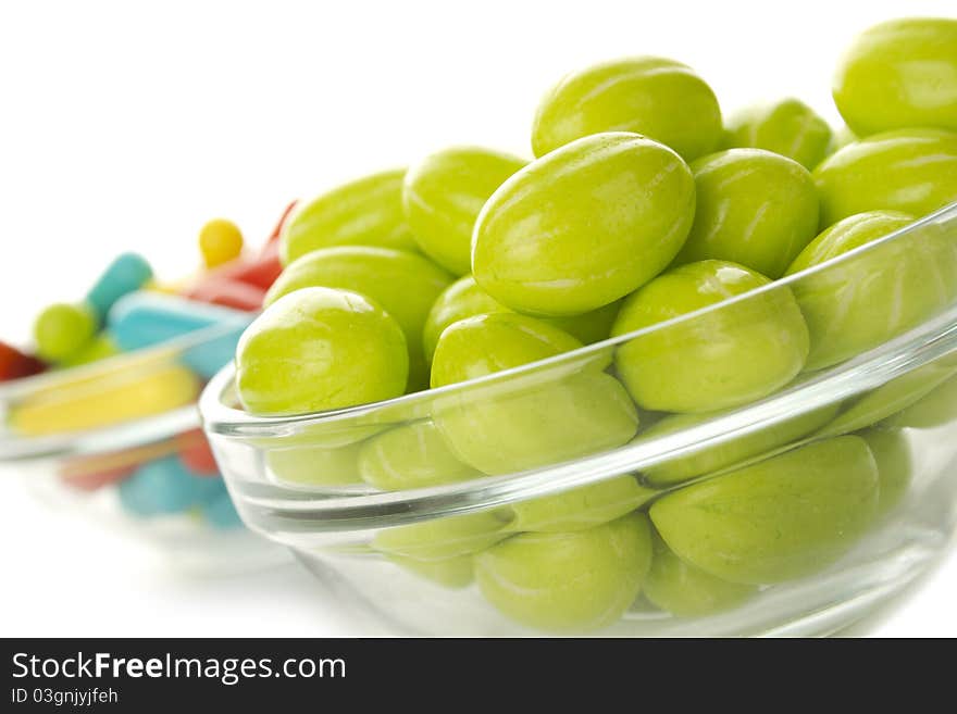 Two glass plates filled to the brim with tasty colorful candies. Isolated. Two glass plates filled to the brim with tasty colorful candies. Isolated