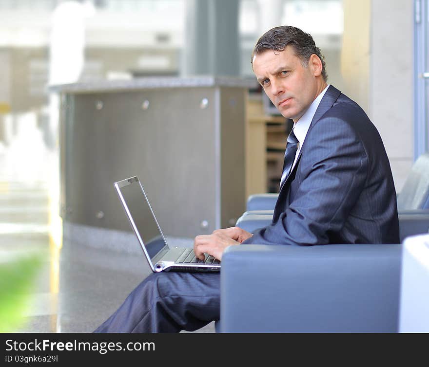 Casual looking businessman working on laptop computer in front of office window