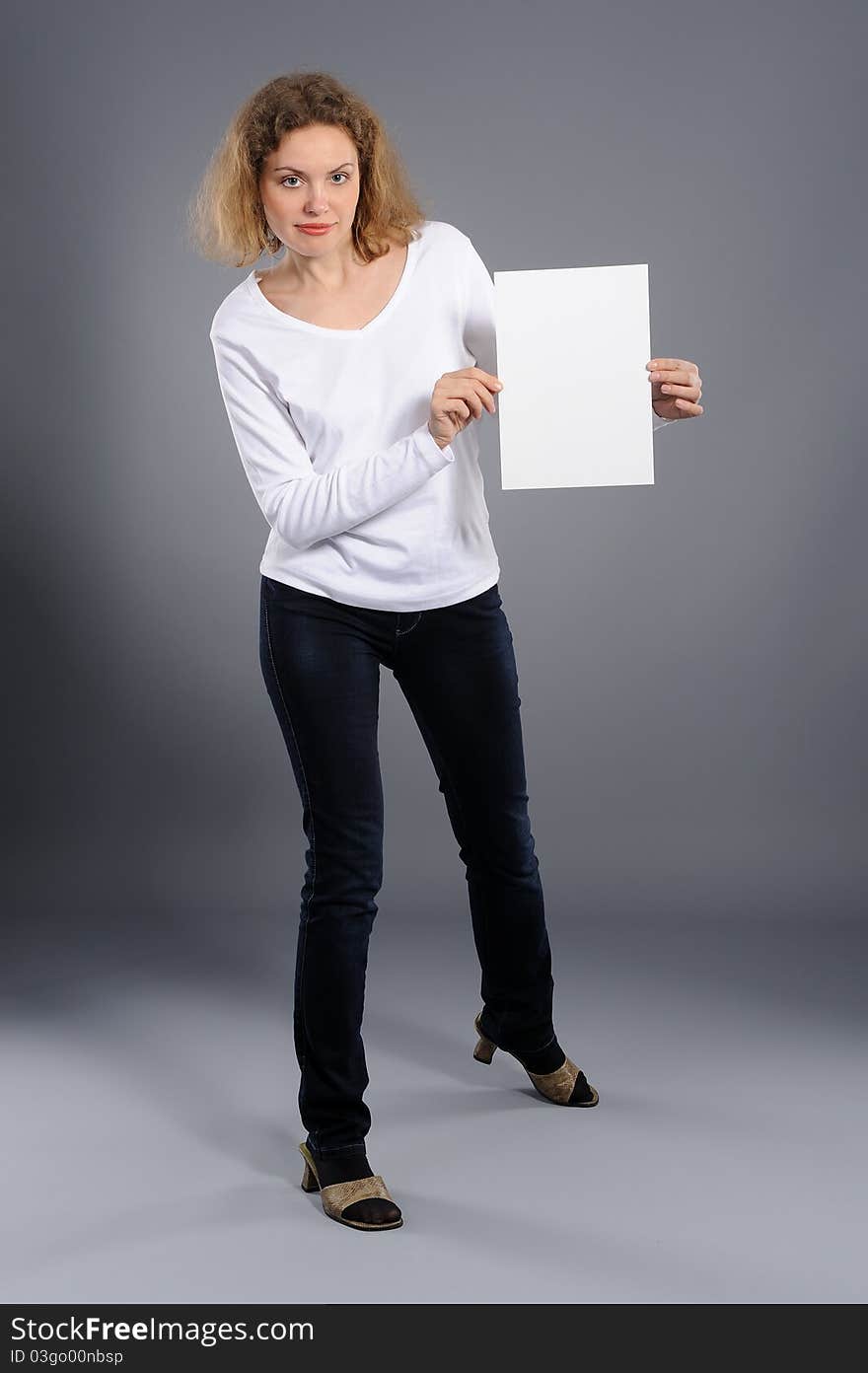 Young woman holding empty white board, on a  grey background