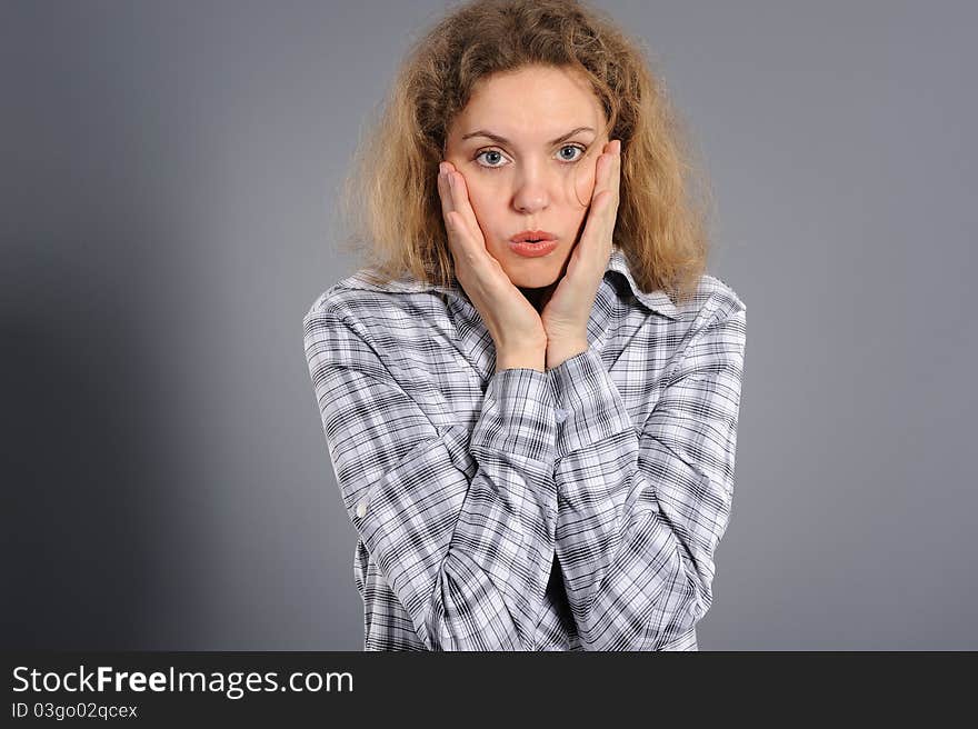 Portrait of attractive young woman looking shocked on a grey background