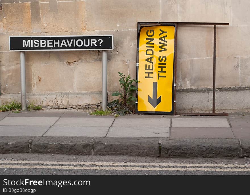 A conceptuall scene involving two British street signs situated on a pavement with block wall behind. A conceptuall scene involving two British street signs situated on a pavement with block wall behind