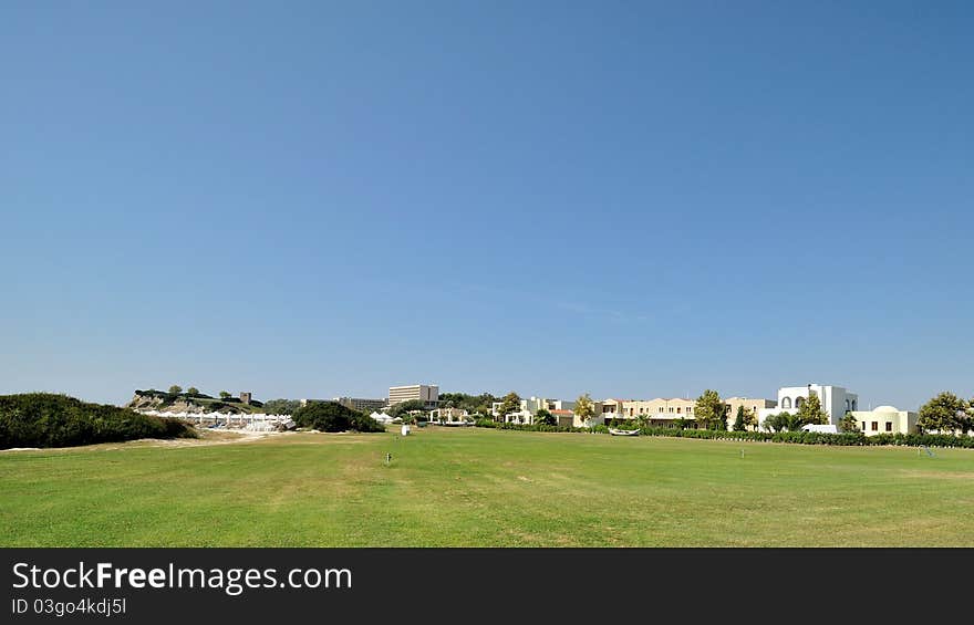 Luxury resort at the seaside, surrounded by a green field.