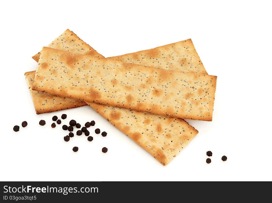 Salt and pepper crackers with loose peppercorns isolated over white background.