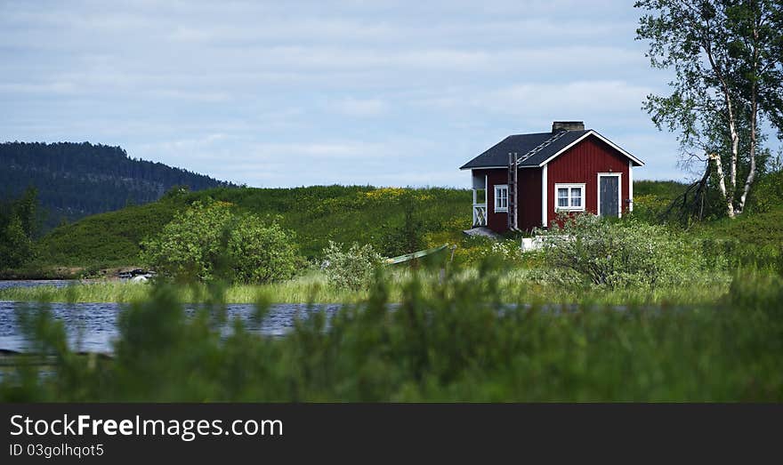 Wooden house in a green, on a riverbank in Lappland. Wooden house in a green, on a riverbank in Lappland