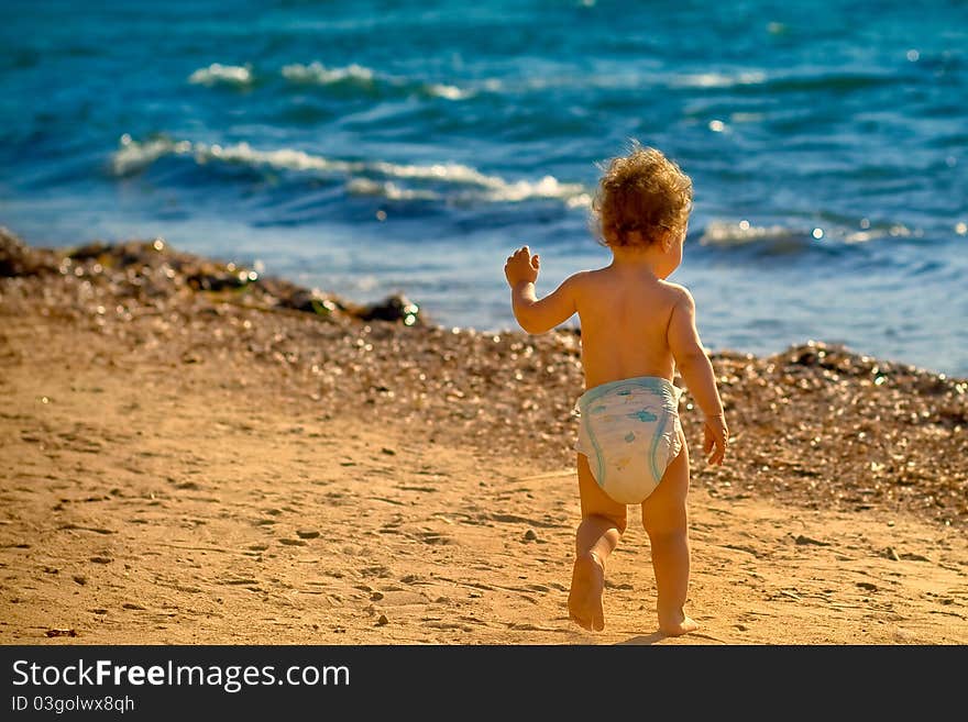 Baby boy running on the sandy beach towards the waves. Baby boy running on the sandy beach towards the waves.