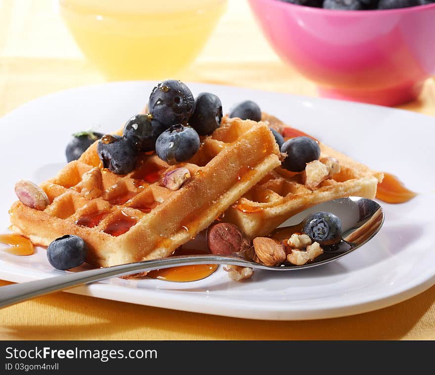 Belgian waffles with fresh blueberries and nuts on white plate