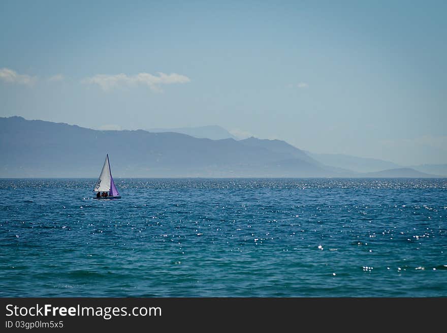 Sailing Boat in blue sea, with mountains in the background. Sailing Boat in blue sea, with mountains in the background