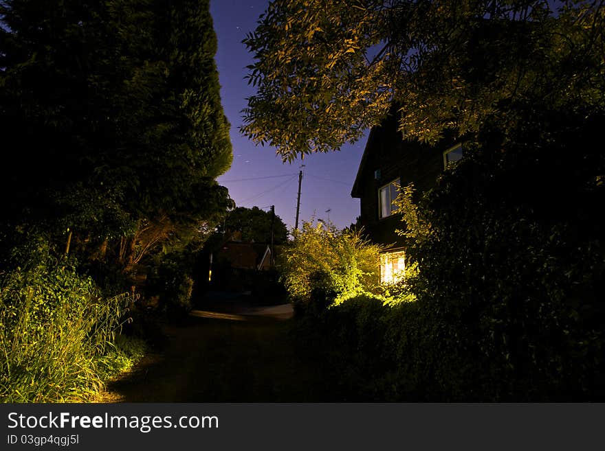 Nighttime scene of a footpath lit by window light. Nighttime scene of a footpath lit by window light