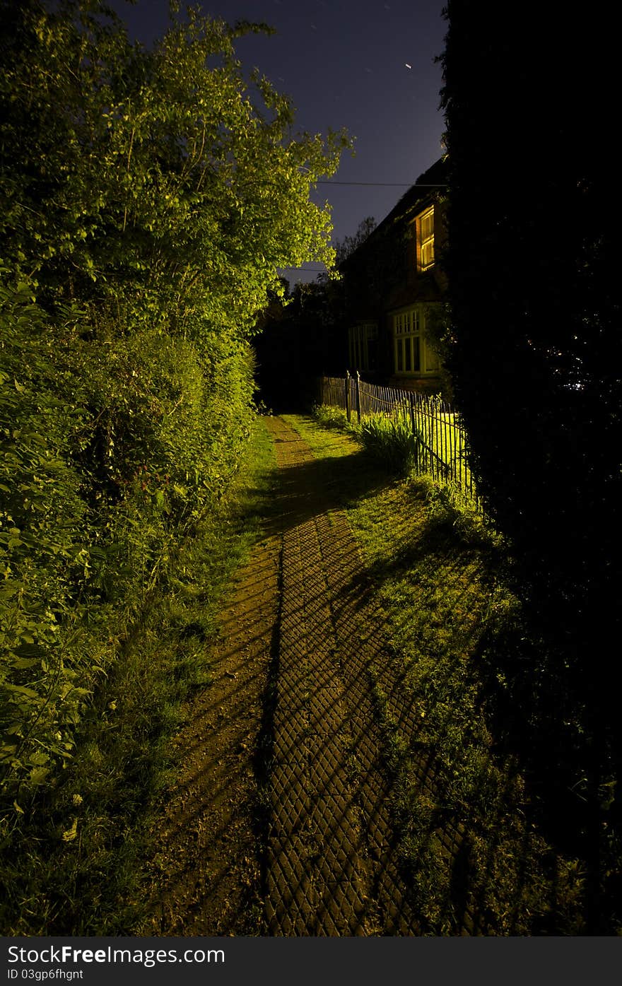 Nighttime scene of a footpath lit by window light. Nighttime scene of a footpath lit by window light