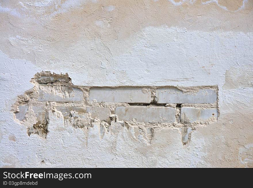 The texture of the wall. A white wall of brick with plaster crashed. The texture of the wall. A white wall of brick with plaster crashed.