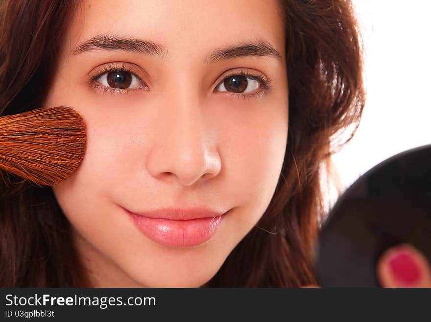 Beautiful young woman making up her face with a small smile on her lips