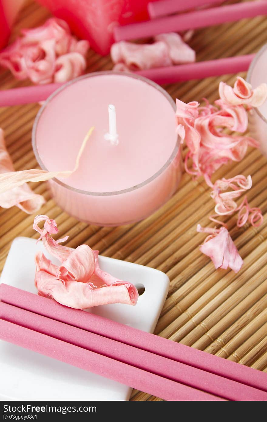 Spa treatment in bright pink and white palette, petals, candles, and arotatizirovannye sticks on a wooden bamboo rug