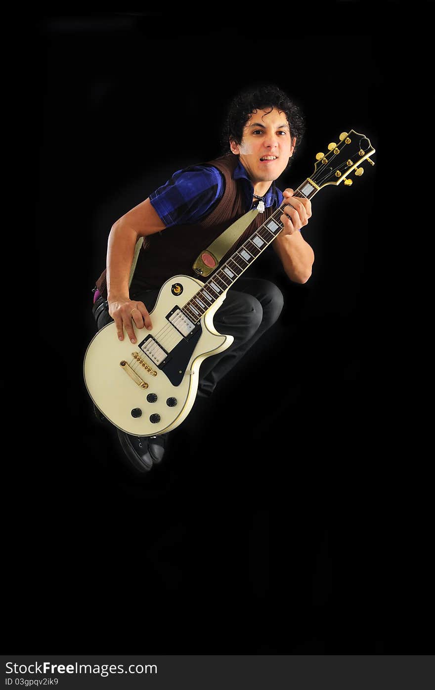 Portrait of young trendy guy jumping with electric guitar isolated on black