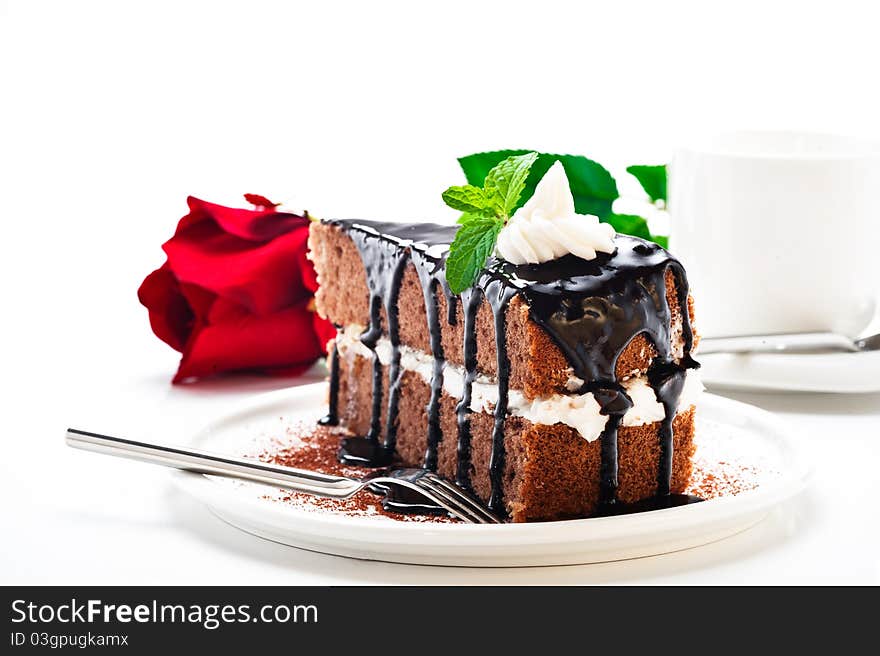 A piece of chocolate cake with vanilla cream and a rose