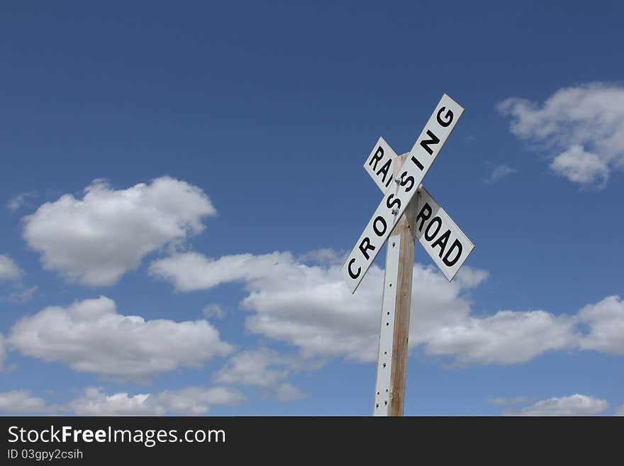 Railroad crossing sign against blue sky