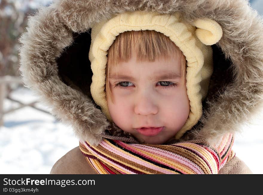 Winter outdoors head and shoulders portrait of a little girl wearing fir-coat with hood and scarf. Winter outdoors head and shoulders portrait of a little girl wearing fir-coat with hood and scarf