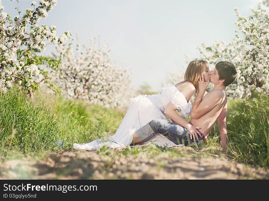 Beautiful young couple kissing in the flowering ga