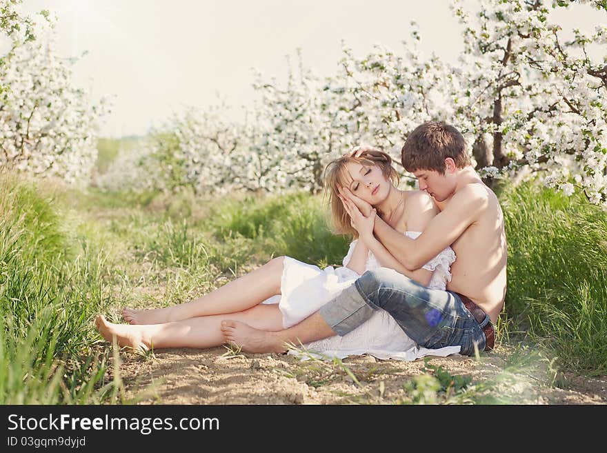 Beautiful young couple kissing in the flowering ga