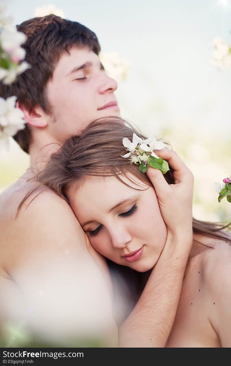 Beautiful young couple kissing in the flowering ga