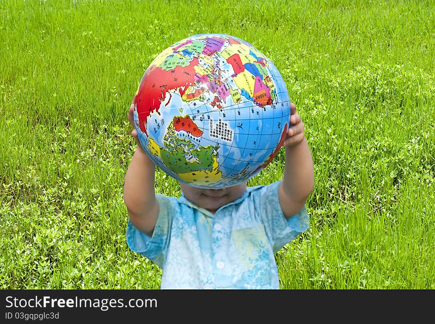 Boy holding the earth model on the grass