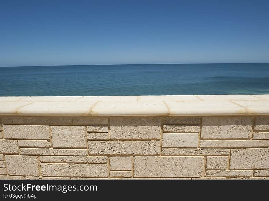 The vast open space of the sheer endless ocean and a clear blue sky behind a limestone wall.