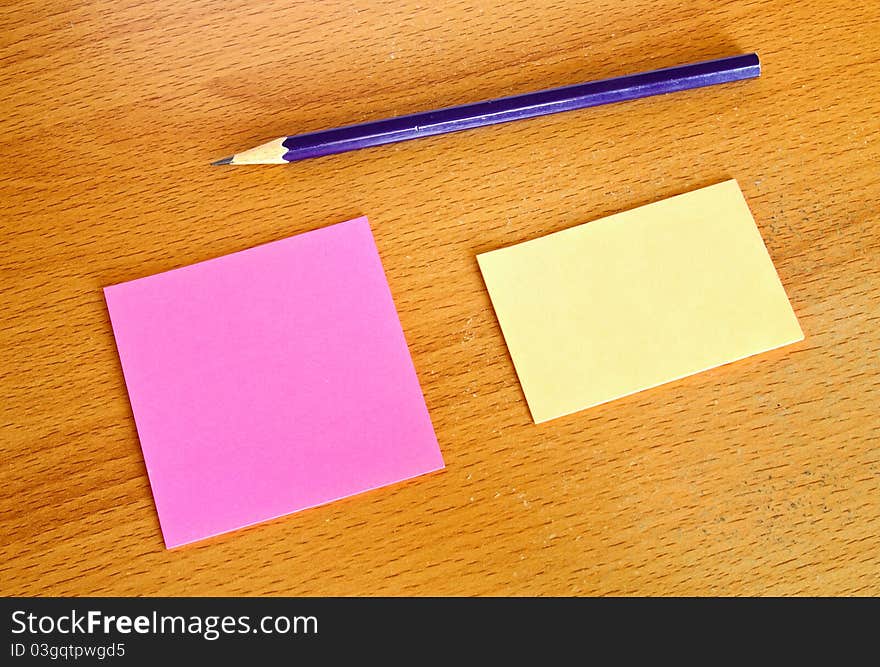 Yellow and pink memo with pencil on wood table