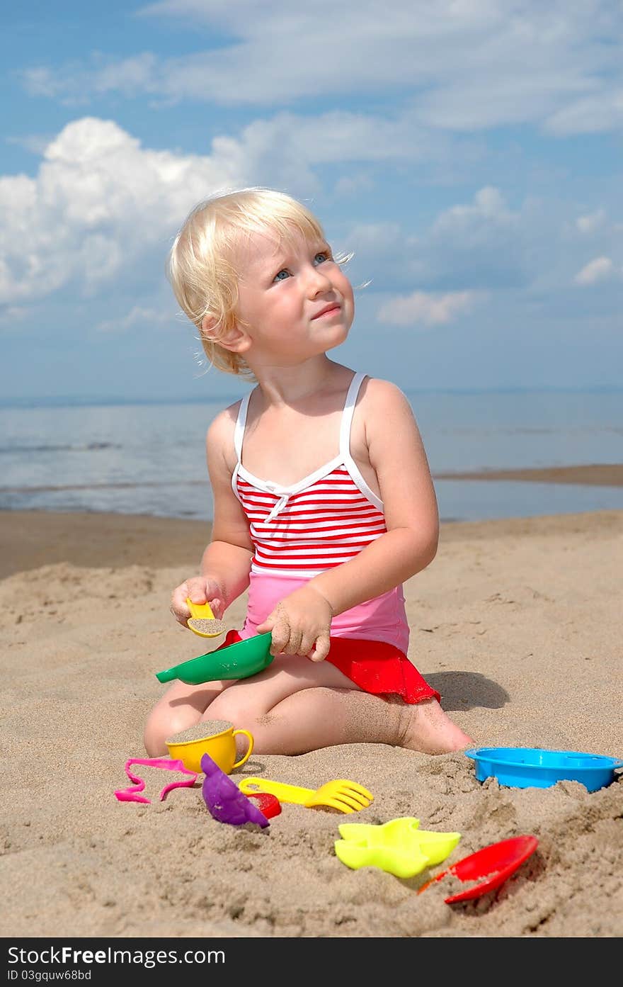 Child plays with toy in sand on beach