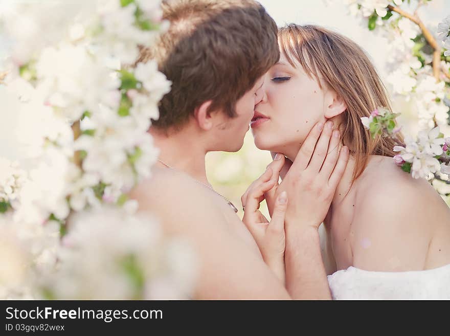 Beautiful young couple kissing in the flowering ga