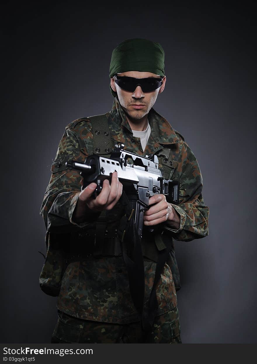 Young soldier in camouflage and ammunition with a gun. studio shot. Young soldier in camouflage and ammunition with a gun. studio shot