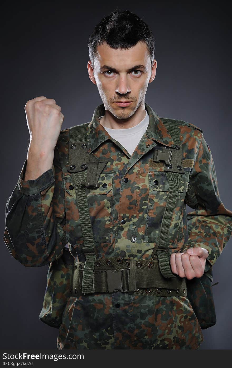 Portrait of soldier in camouflage and ammunition fighting. studio shot