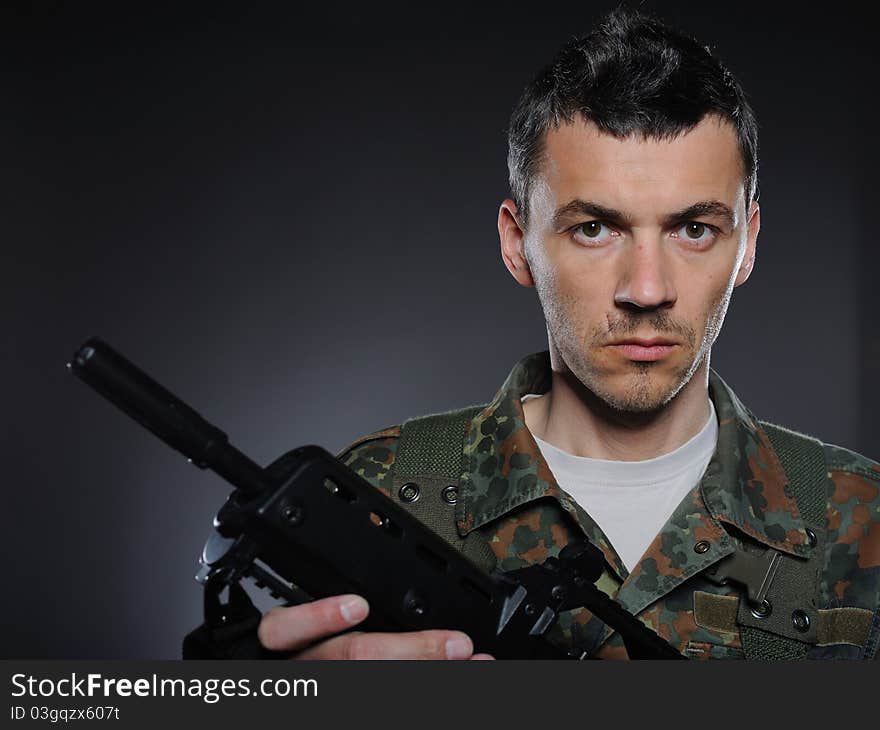 Young soldier in camouflage and ammunition with a gun. studio shot. Young soldier in camouflage and ammunition with a gun. studio shot