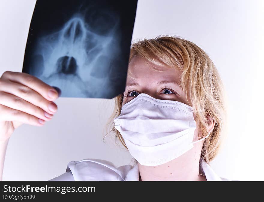 Serious female doctor looking at a x-ray against white background