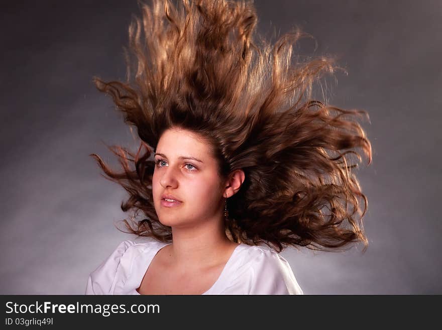 Young brunette woman with long flying hair, studio shot