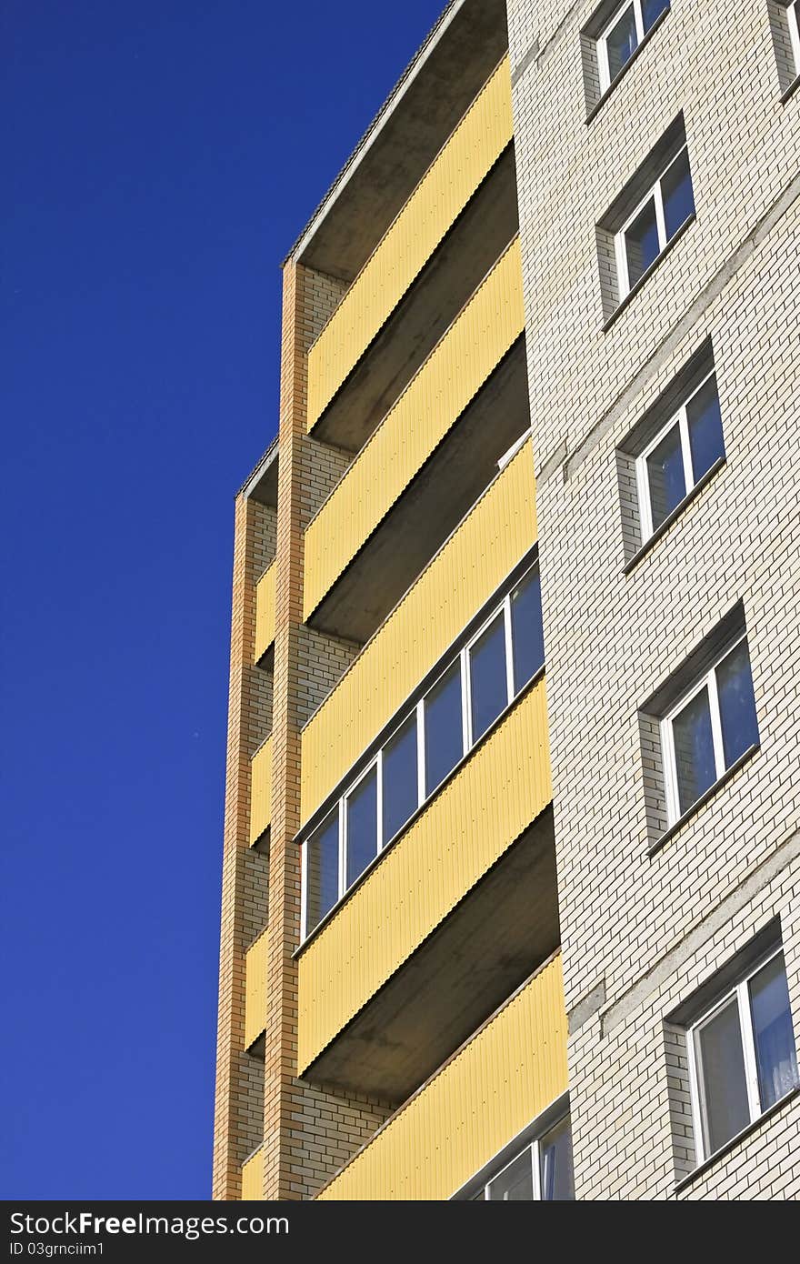 High building with a yellow facade against the blue sky. High building with a yellow facade against the blue sky