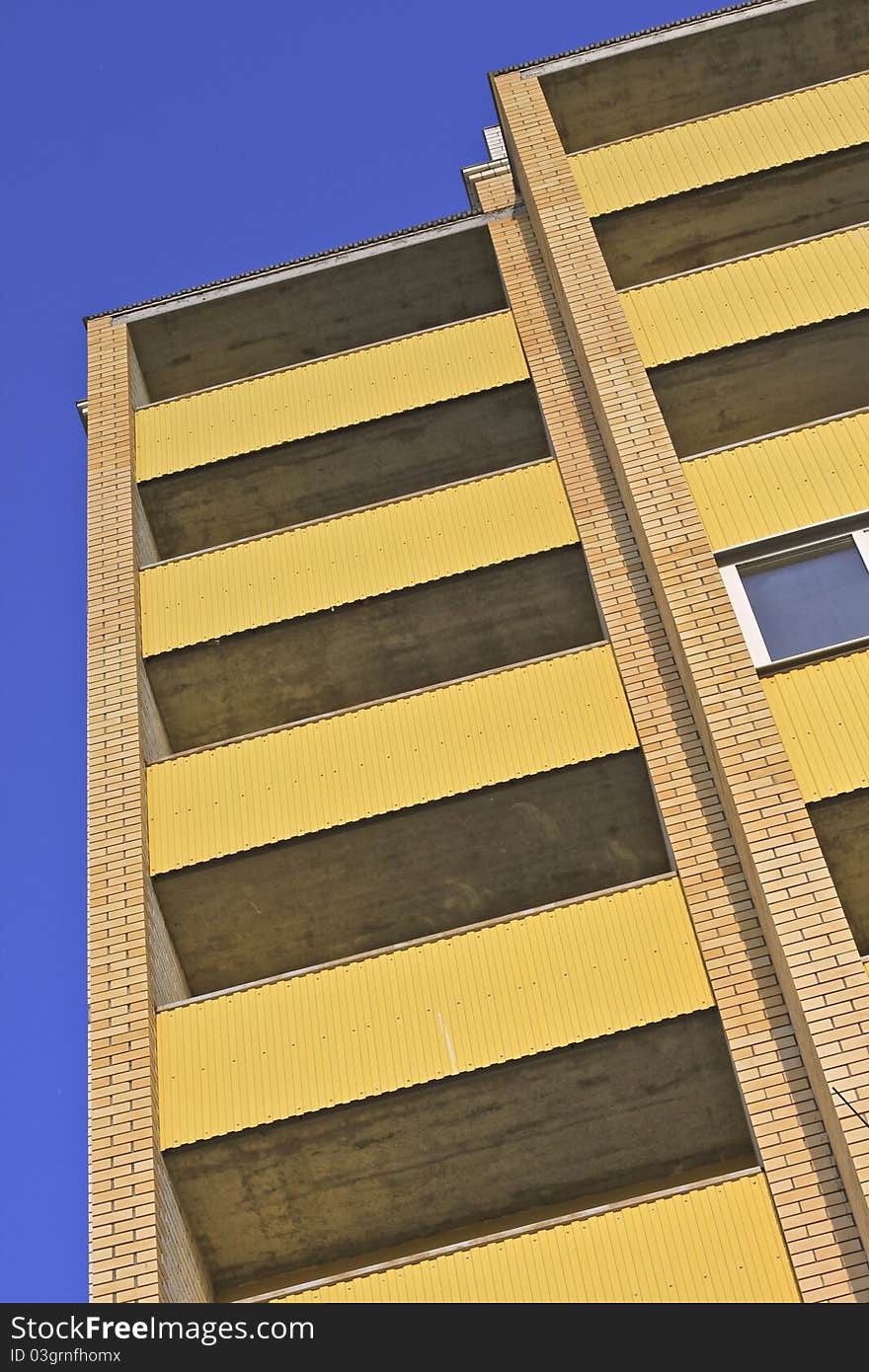 High building with a yellow facade against the blue sky. High building with a yellow facade against the blue sky