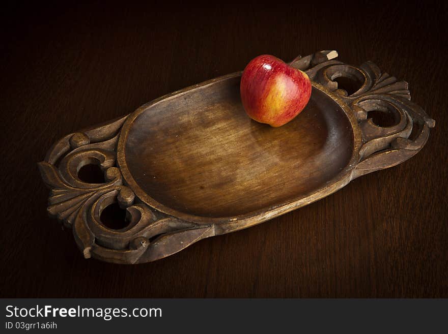 Brightly red apple on an ancient wooden dish. Brightly red apple on an ancient wooden dish