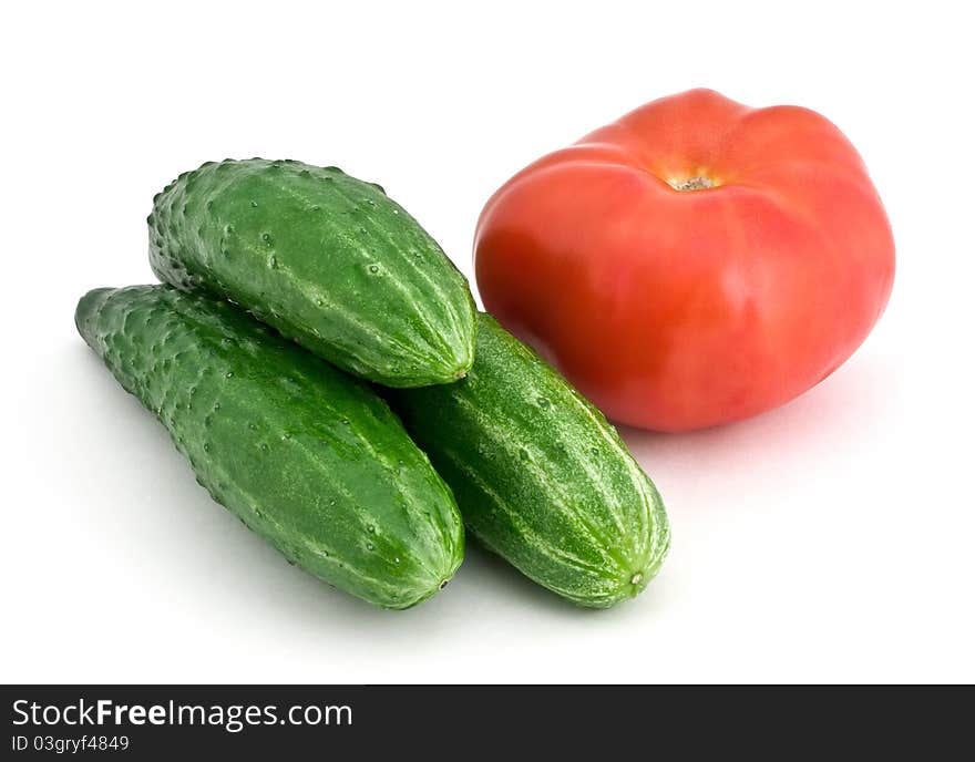 Three cucumbers and tomato isolated on white background