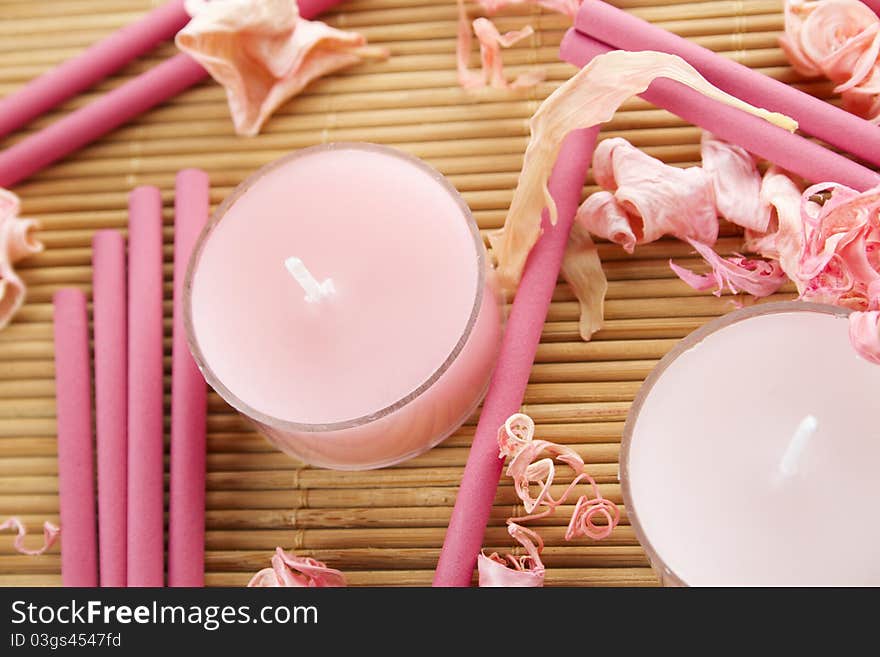 Spa treatment in bright pink and white palette, petals, candles, and arotatizirovannye sticks on a wooden bamboo rug