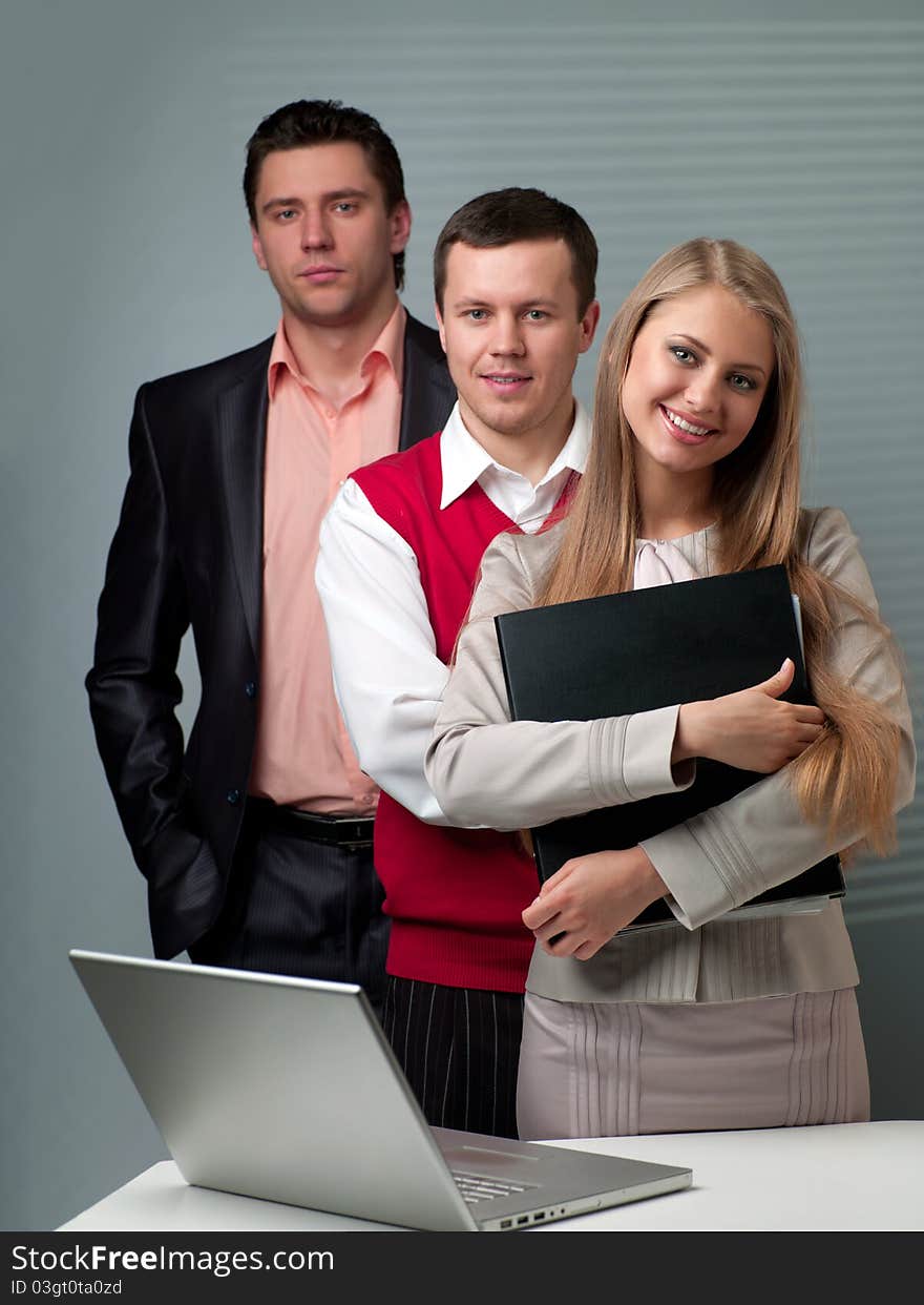 Two men and woman working with a computer in the office