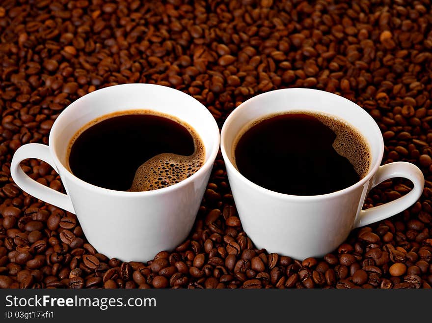 Two cups of coffee on roasted coffee beans. Two cups of coffee on roasted coffee beans