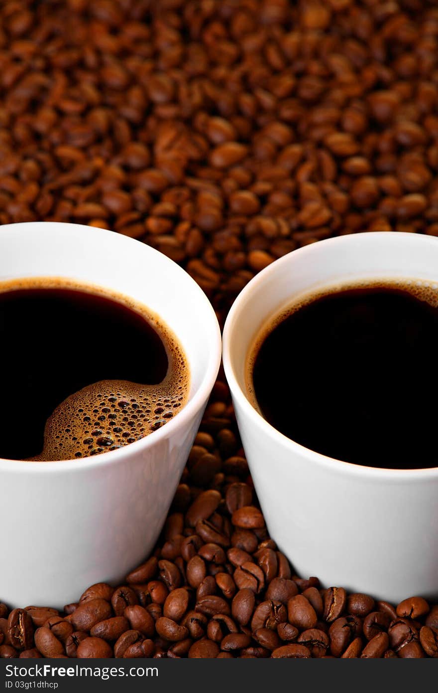 Two cups of coffee on roasted coffee beans. Two cups of coffee on roasted coffee beans