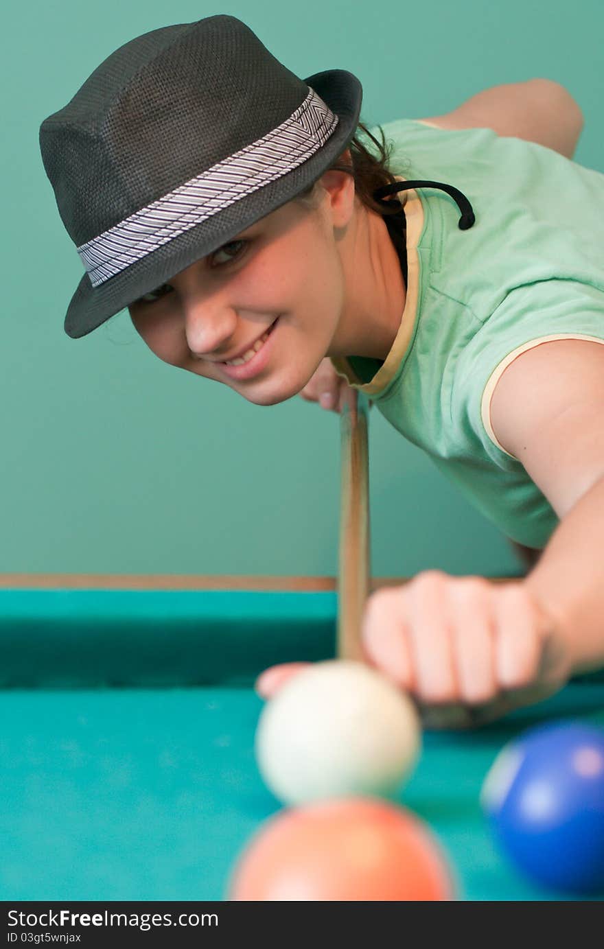 Young woman in hat playing billiards. Young woman in hat playing billiards