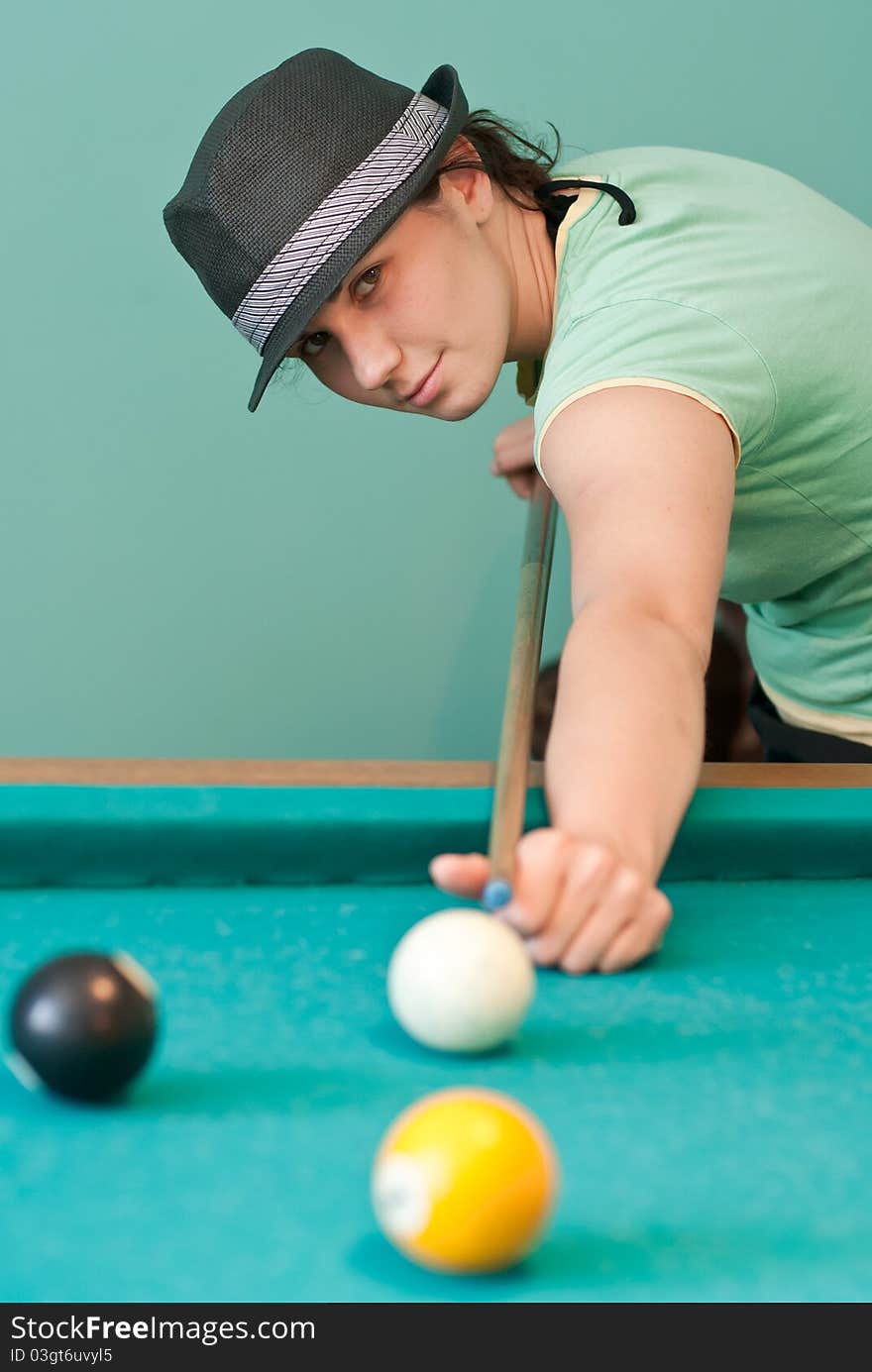 Young woman in hat playing billiards. Young woman in hat playing billiards