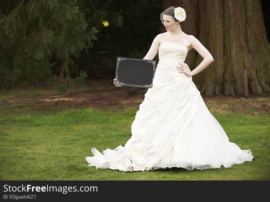 Pretty bride in wedding dress holding a blank board with space for copy. Pretty bride in wedding dress holding a blank board with space for copy